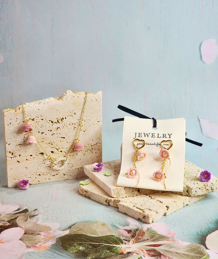 Lily of the Valley Collection featuring micro-crochet accessories with pearls. Featured a pearl necklace with pink micro-crochet Lilies of the Valley and earrings. 18K gold-plated.