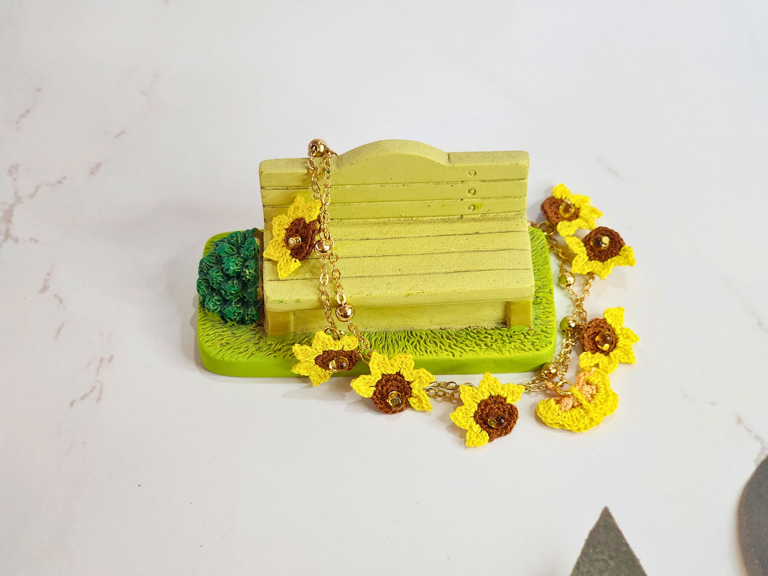 Handcrafted micro-crochet bracelet featuring half sunflowers & butterflies in yellow and orange tones. Accessorised with Miyuki waterdrop beads from Japan and 18K gold-plated chain.