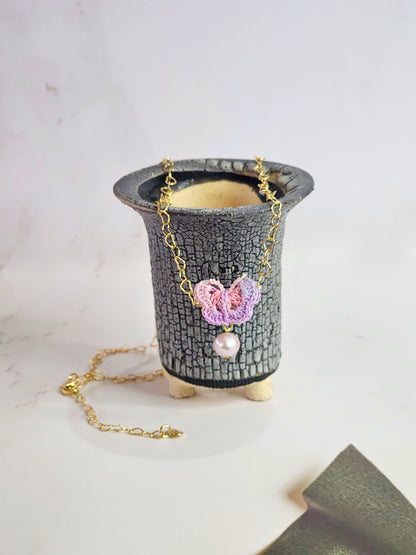 Handcrafted micro-crochet butterfly adorned with an 8mm purple freshwater pearl. Set on 14K gold-filled heart-shaped necklace.
