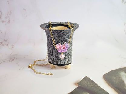 Handcrafted micro-crochet butterfly adorned with an 8mm purple freshwater pearl. Set on 14K gold-filled heart-shaped necklace.