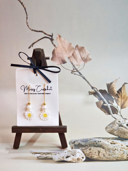 Handcrafted micro-crochet daisies earrings accented with freshwater pearls & gold beads. Styled with 18K gold-plated tassel hooks.