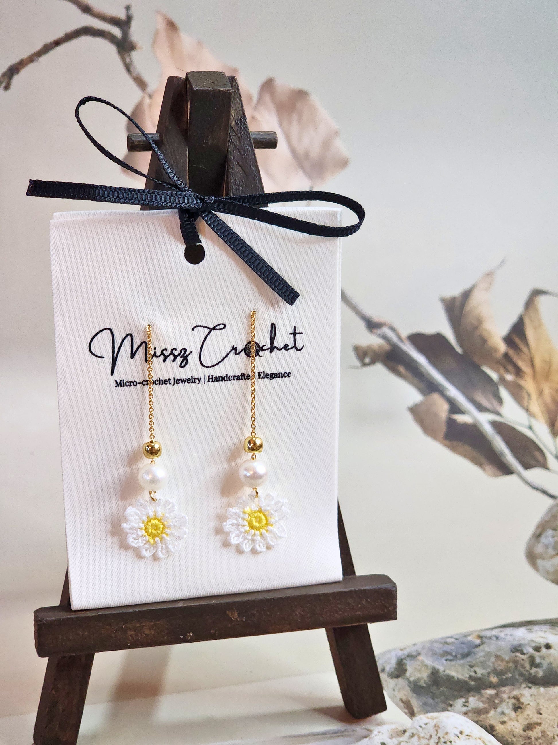 Handcrafted micro-crochet daisies earrings accented with freshwater pearls & gold beads. Styled with 18K gold-plated tassel hooks.