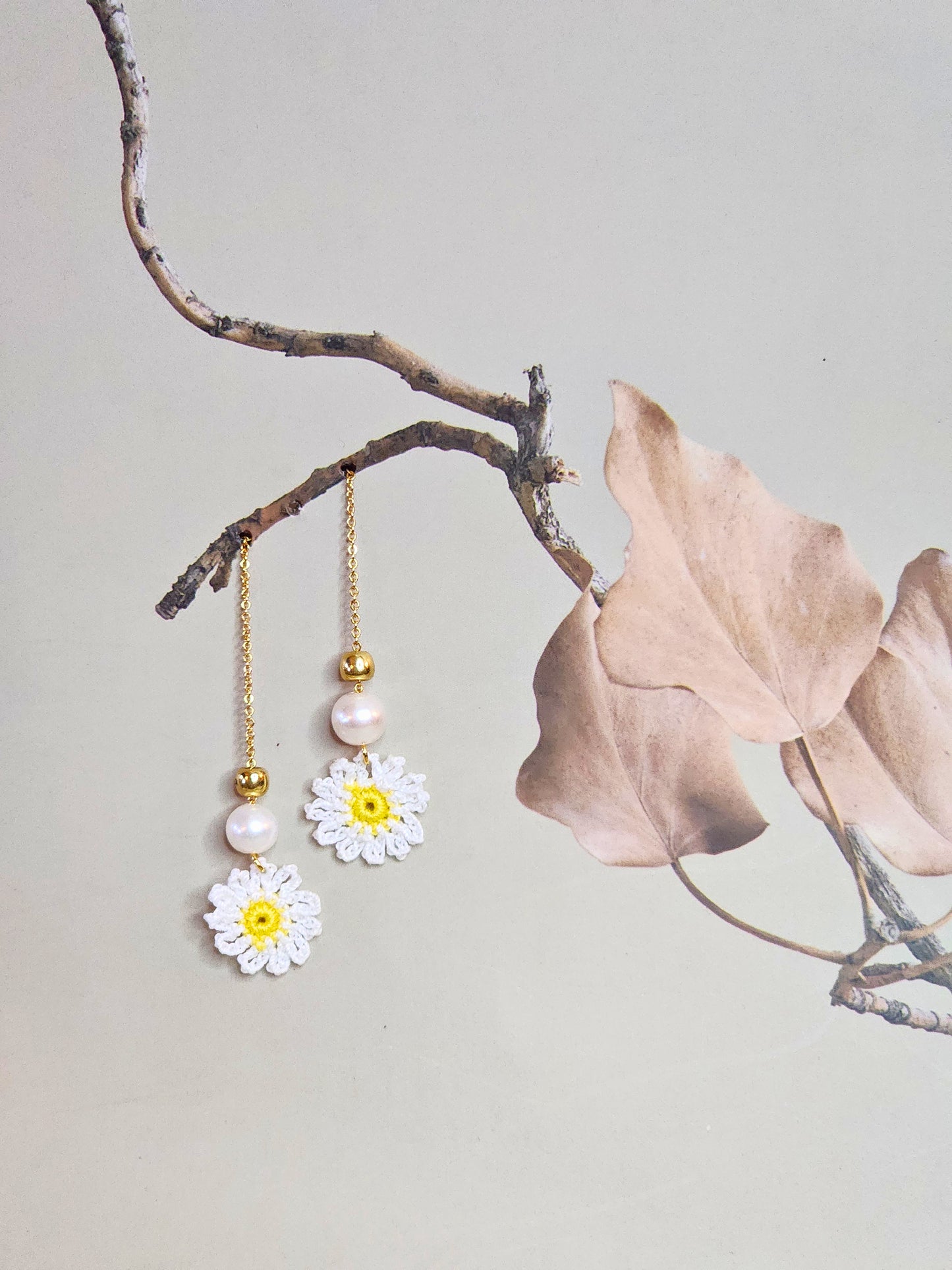 Handcrafted micro-crochet daisies earrings accented with freshwater pearls & gold beads. Styled with 18K gold-plated tassel hooks.