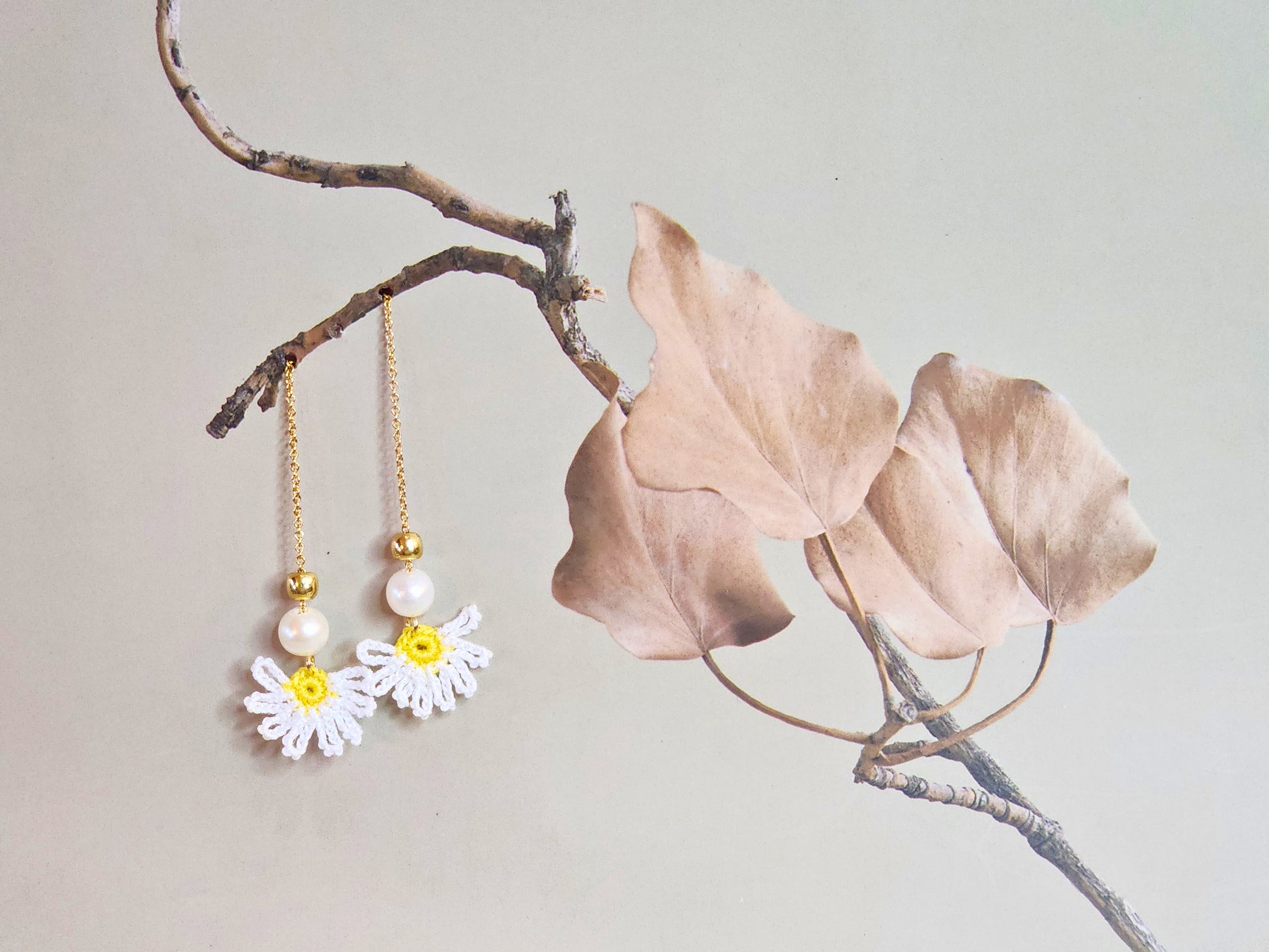 Handcrafted micro-crochet daisies earrings accented with freshwater pearls & gold beads. Styled with 18K gold-plated tassel hooks.  