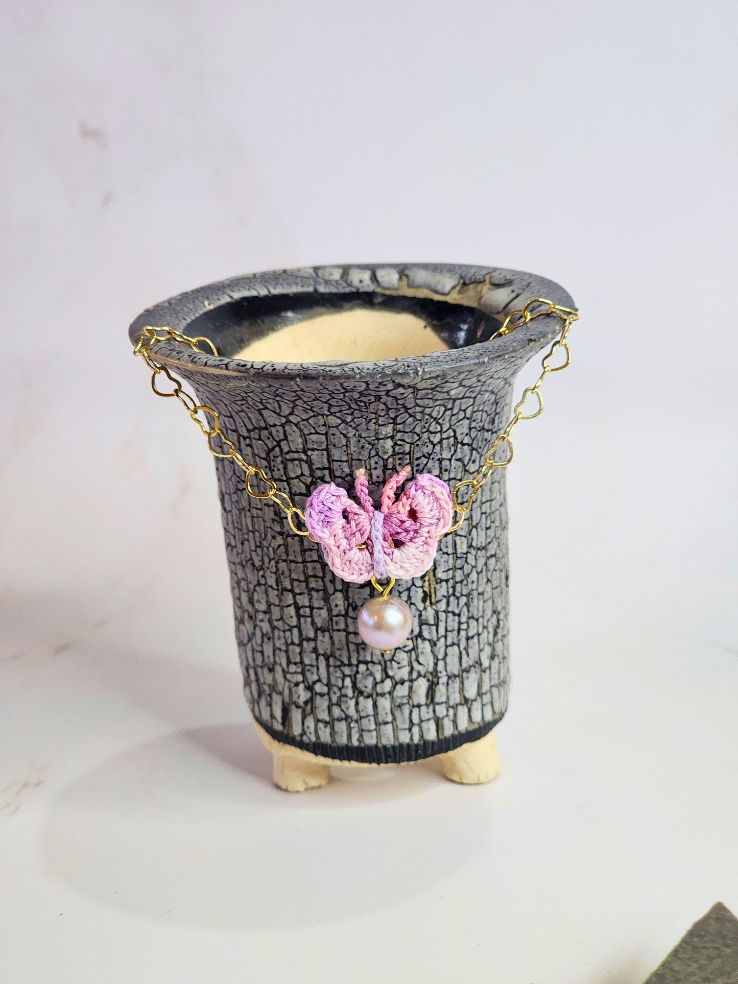 Handcrafted micro-crochet butterfly with 8mm purple freshwater pearl, set on 14K gold-filled heart-shaped bracelet.