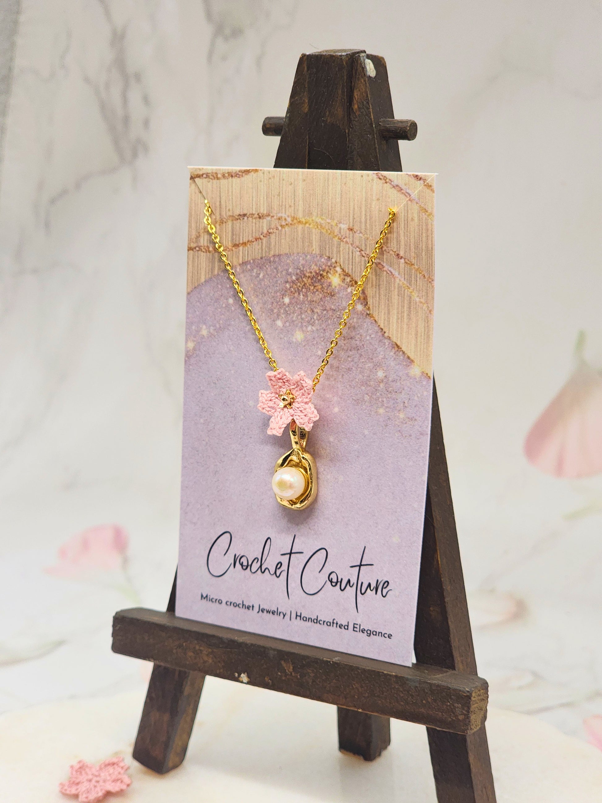 Handcrafted micro crochet Sakura with a lustrous 6–7mm Akoya pearl, suspended from a graceful pendant. Styled with 18K gold-plated pendant and chain. 