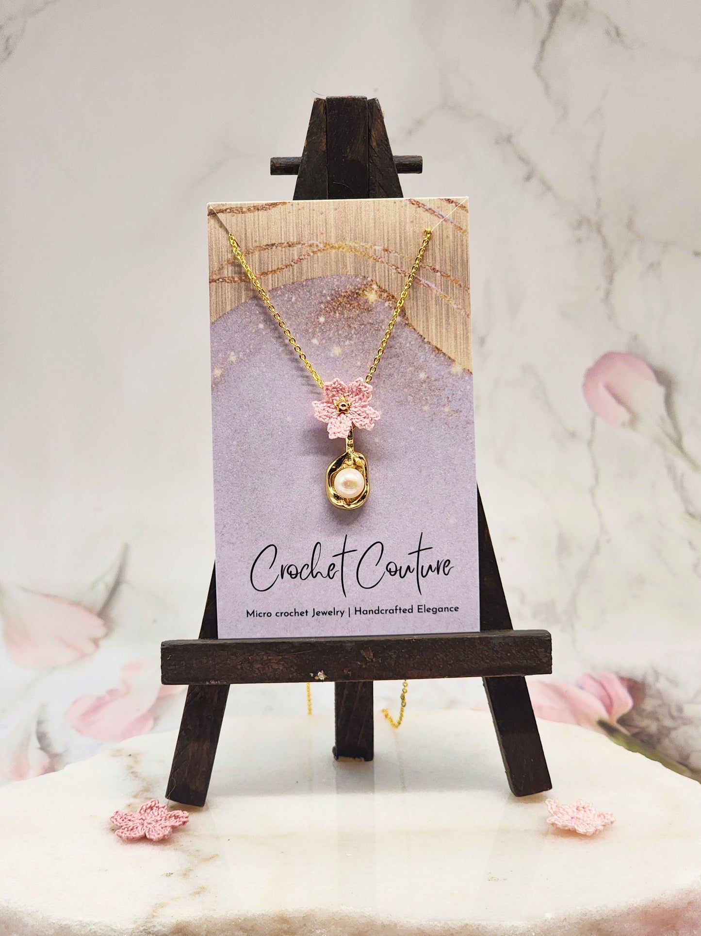 Handcrafted micro crochet Sakura with a lustrous 6–7mm Akoya pearl, suspended from a graceful pendant. Styled with 18K gold-plated pendant and chain. 
