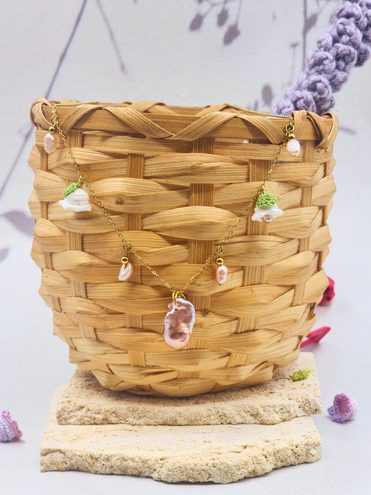 Handcfrafted vintage-style necklace featuring a centrepiece purple-pink metallic Baroque pearl, flanked by pink baroque pearls and micro crochet white lily of the valley blooms. 18K gold-plated titanium stell chain. 