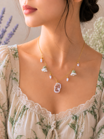 Handcfrafted vintage-style necklace featuring a centrepiece purple-pink metallic Baroque pearl, flanked by pink baroque pearls and micro crochet white lily of the valley blooms. 18K gold-plated titanium stell chain.