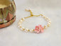 Natural Baroque pearls bracelet centered with a trio of pink micro-crochet peach blossoms. 18K gold-plated slider chain. 
