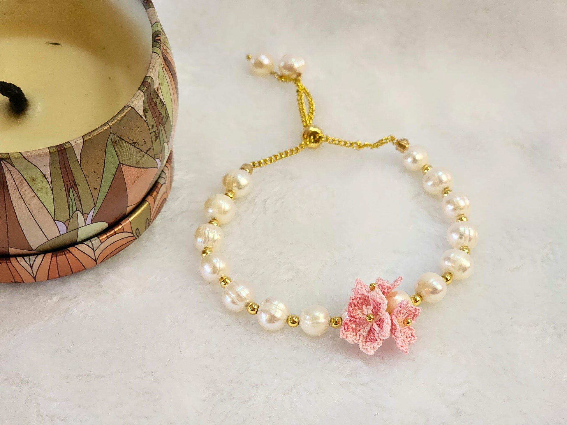 Natural Baroque pearls bracelet centered with a trio of pink micro-crochet peach blossoms. 18K gold-plated slider chain. 