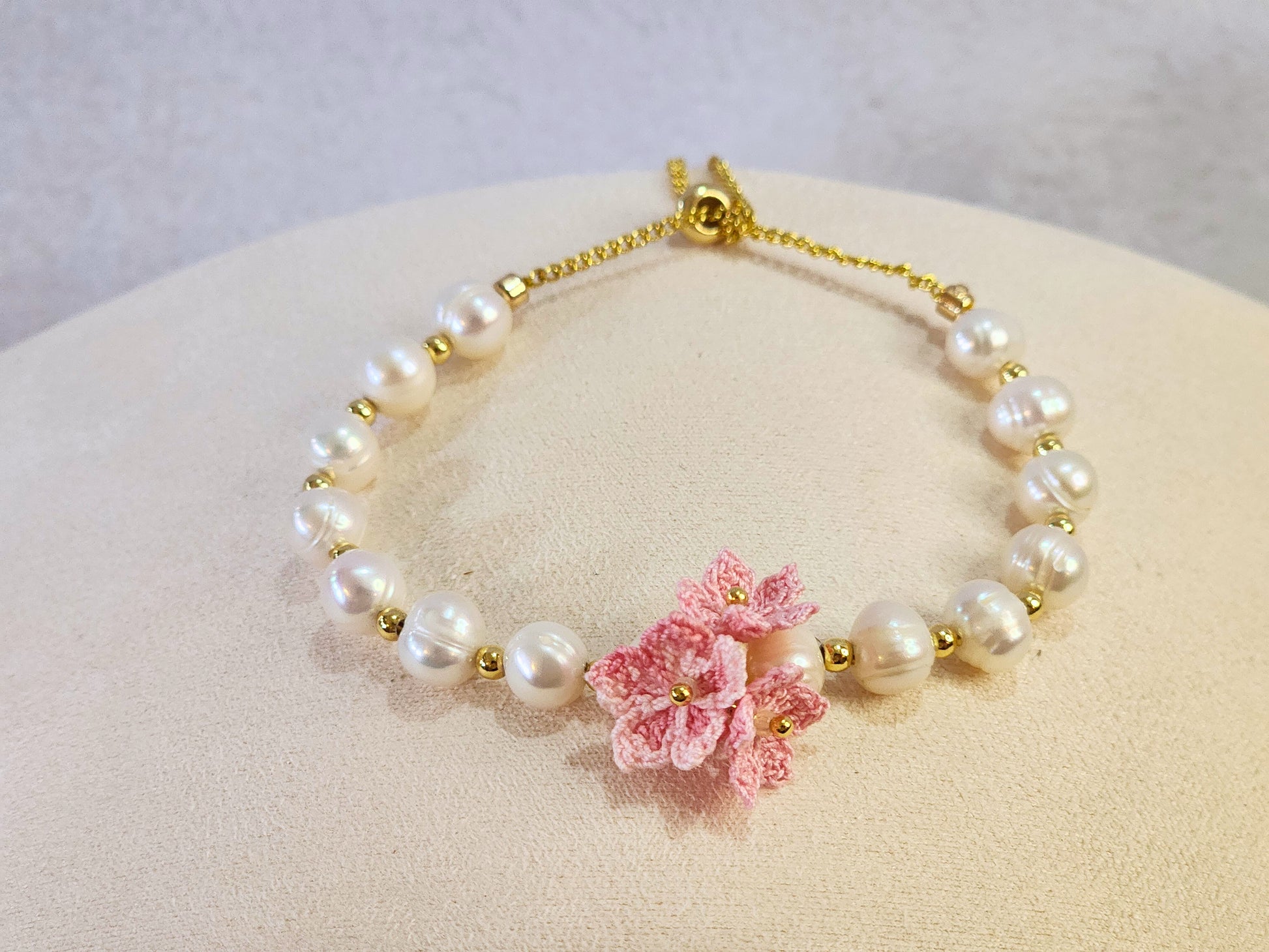 Natural Baroque pearls bracelet centered with a trio of pink micro-crochet peach blossoms. 18K gold-plated slider chain. 