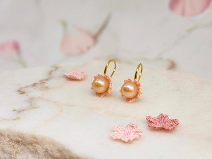 Luminous pink-orange Edison pearls nestled within delicate micro crochet Sakura blossoms. Styled with 18K gold-plated lace motif hooks. 