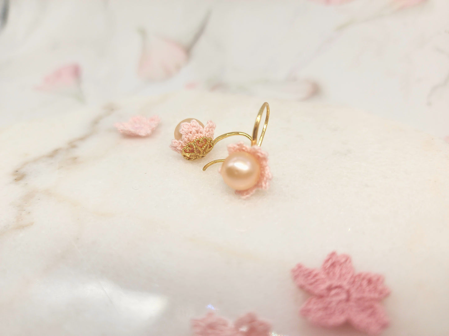 Luminous pink-orange Edison pearls nestled within delicate micro crochet Sakura blossoms. Styled with 18K gold-plated lace motif hooks. 