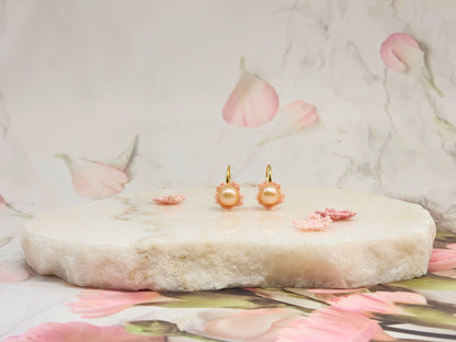 Luminous pink-orange Edison pearls nestled within delicate micro crochet Sakura blossoms. Styled with 18K gold-plated lace motif hooks. 