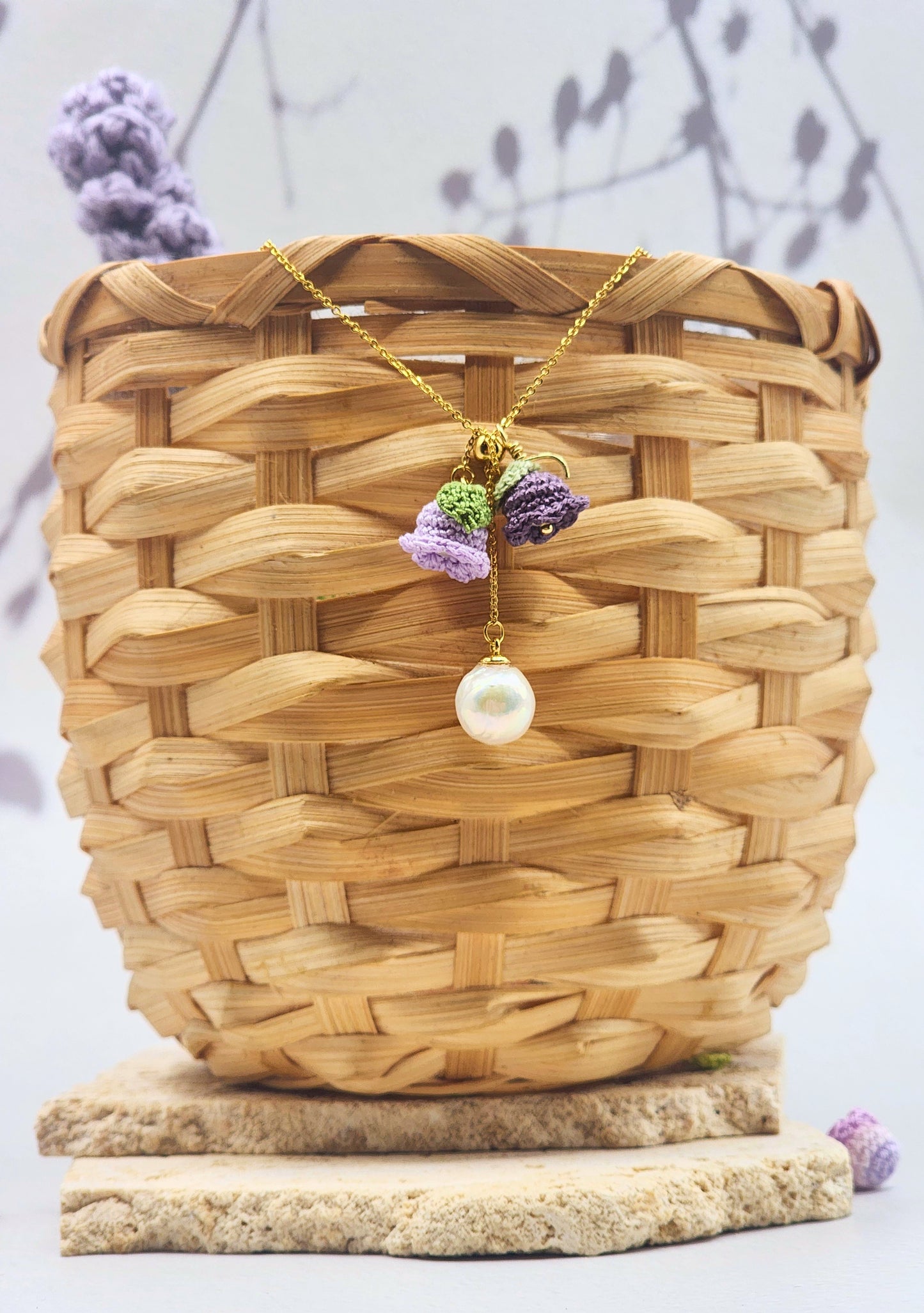 Handcrafted necklace featuring a centre hanging 10mm freshwater Baroque pearl flanked by purple micro crochet Lily of the Valley blooms crowned with 6mm Aurora pearls. 18K gold-plated chain. 