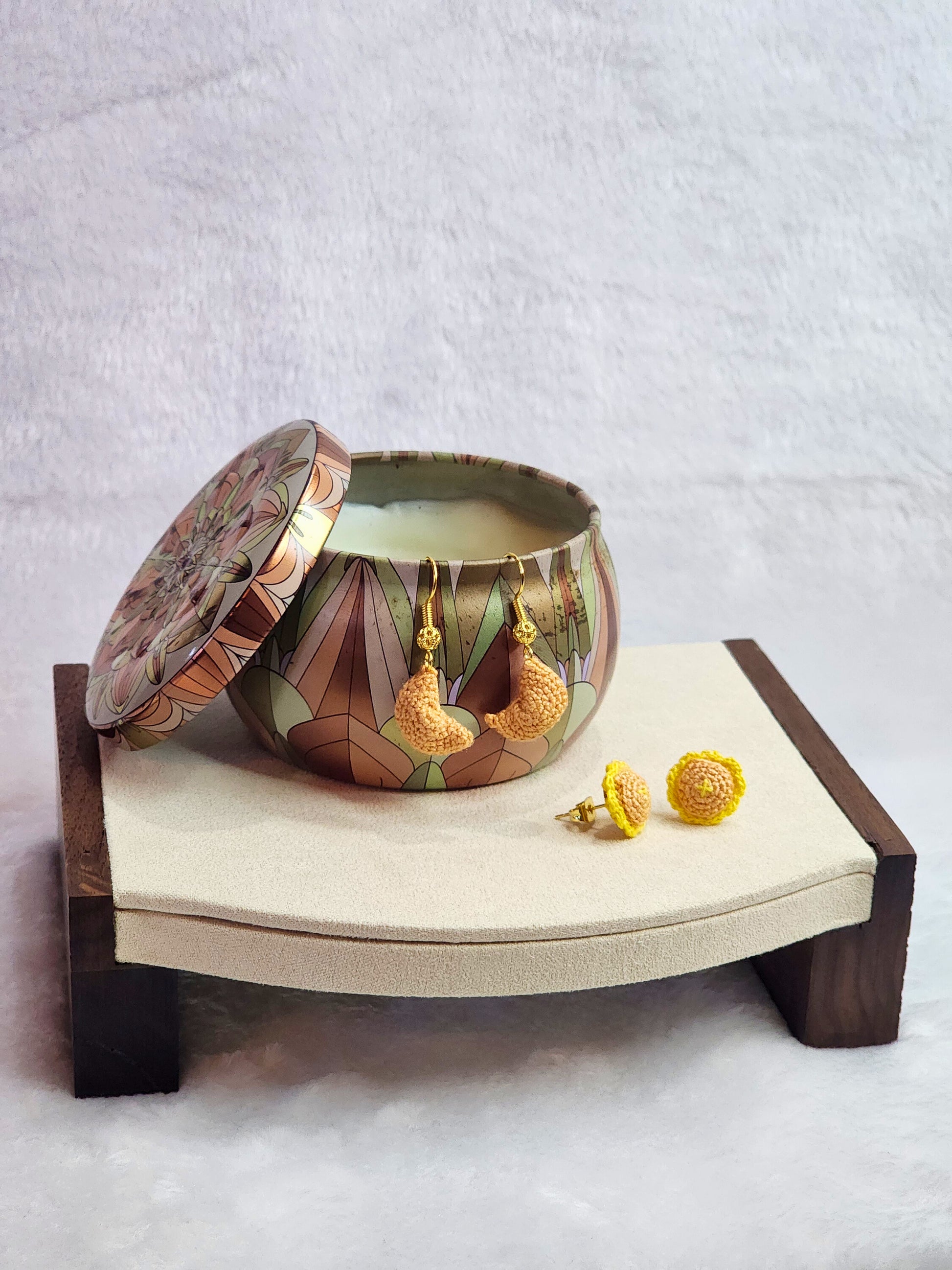 Handcrafted micro-crochet fortune cookie earrings dangling from 18K gold-plated ear hooks