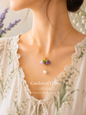 Handcrafted necklace featuring a centre hanging 10mm freshwater Baroque pearl flanked by purple micro crochet Lily of the Valley blooms crowned with 6mm Aurora pearls. 18K gold-plated chain. 