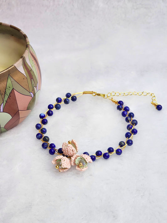 Natural Lapis Lazuli crystal bracelet with a cluster of micro-crochet snowdrops. On 14K gold-plated bangle with extension chain. 