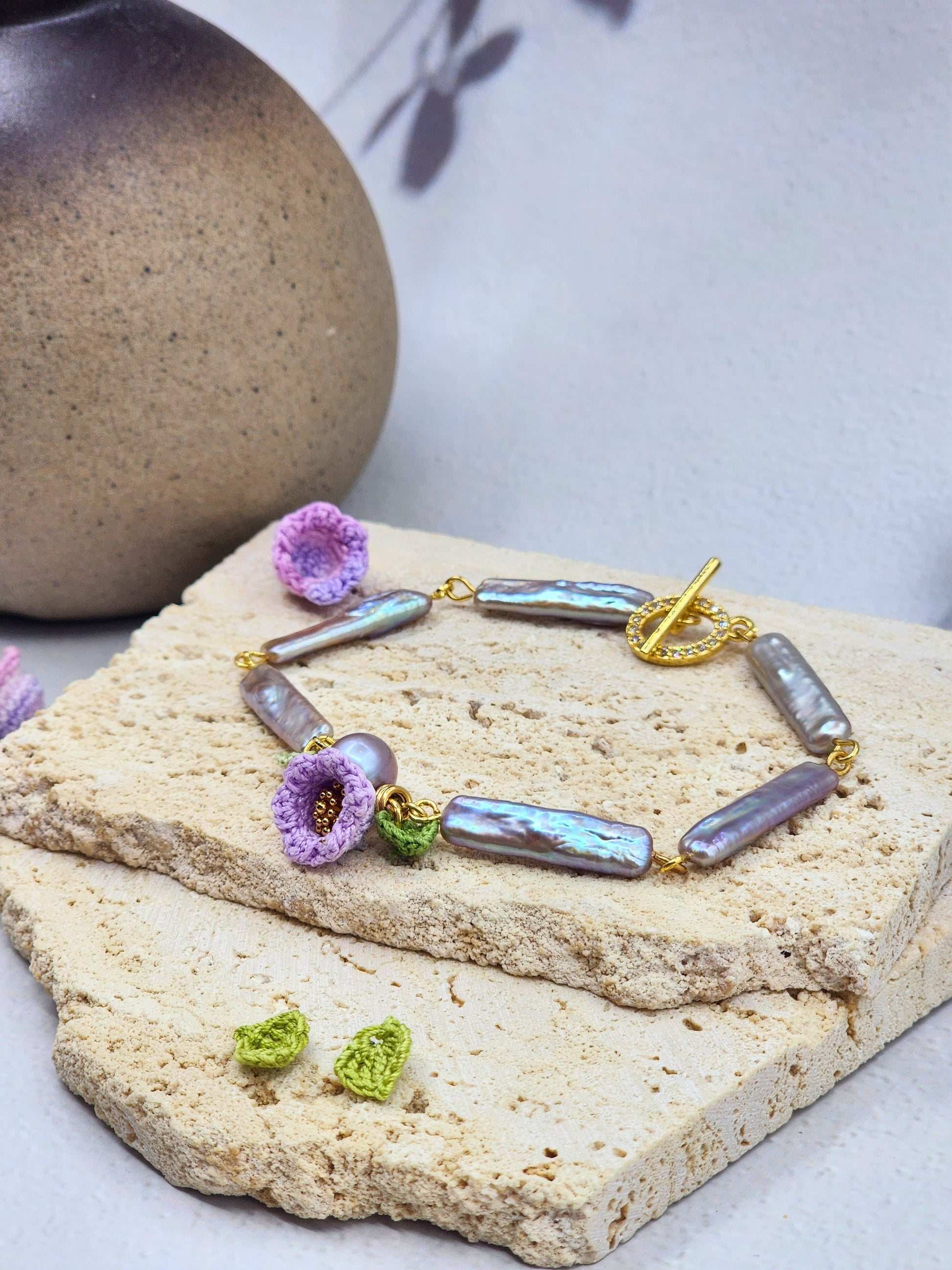 Handcrafted Lily of the Valley blooms bracelet, framing striking silver-grey Pipa pearls and an 8-9mm metallic Edison pearl. 18K gold-plated. 