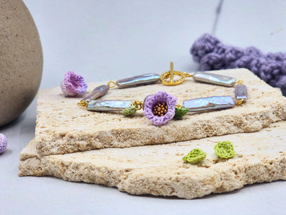 Handcrafted Lily of the Valley blooms bracelet, framing striking silver-grey Pipa pearls and an 8-9mm metallic Edison pearl. 18K gold-plated. 