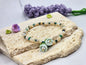 Handcrafted micro crochet Lily of the Valley blooms paired with radiant 4–5mm freshwater Keshi pearls bracelet. Natural Phoenix stones accents.