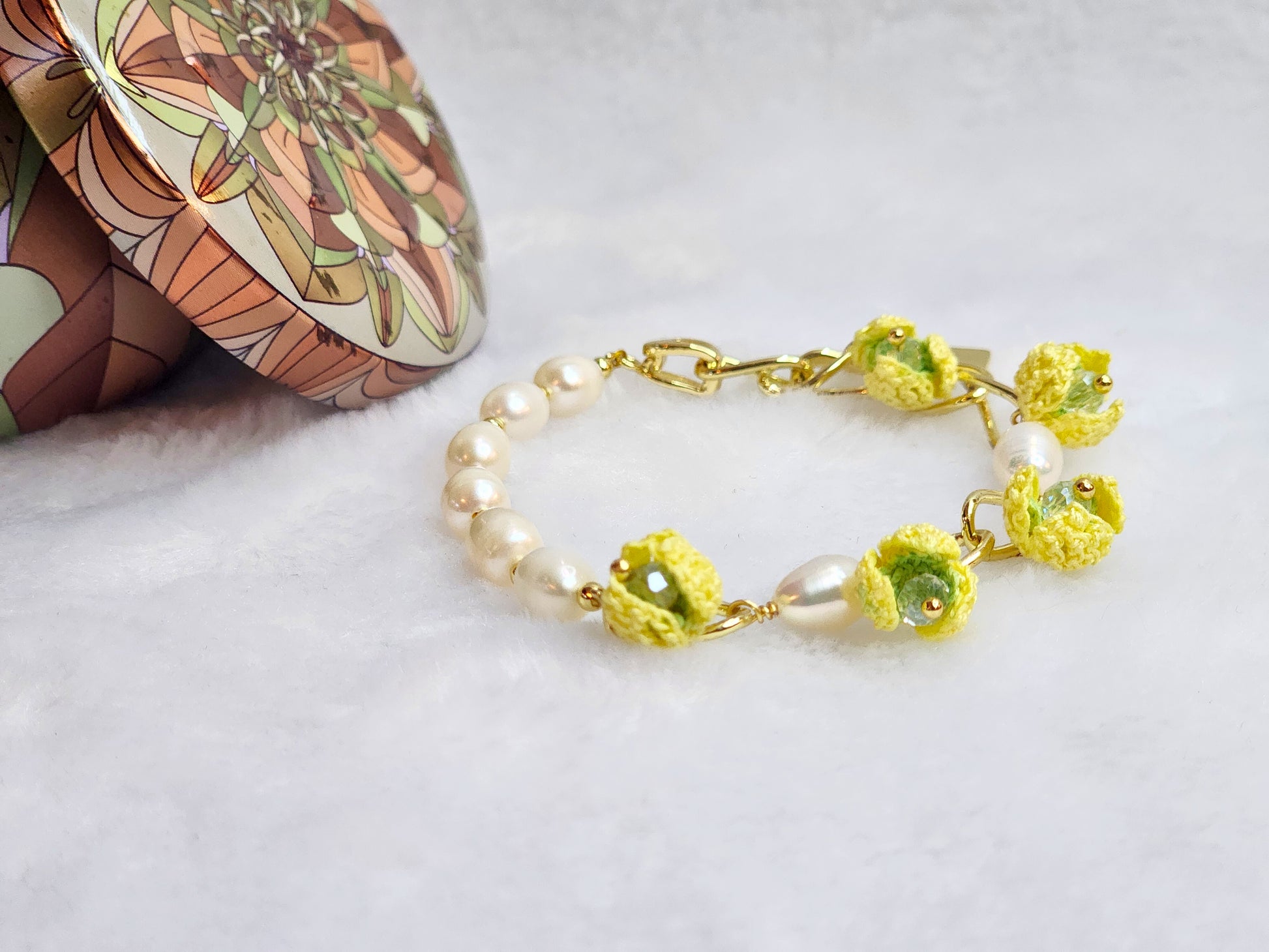 Luminous pearl bracelet with 18K gold-plated chain links on which micro-crochet snowdrops hang. 