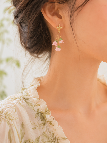 A trio of handcrafted pink micro crochet Lily of the Valley blooms cascade gracefully, each delicately crowned with luminous 6mm Aurora pearls and a sparkling Czech crystal. Finished with 18K gold-plated hooks and findings.