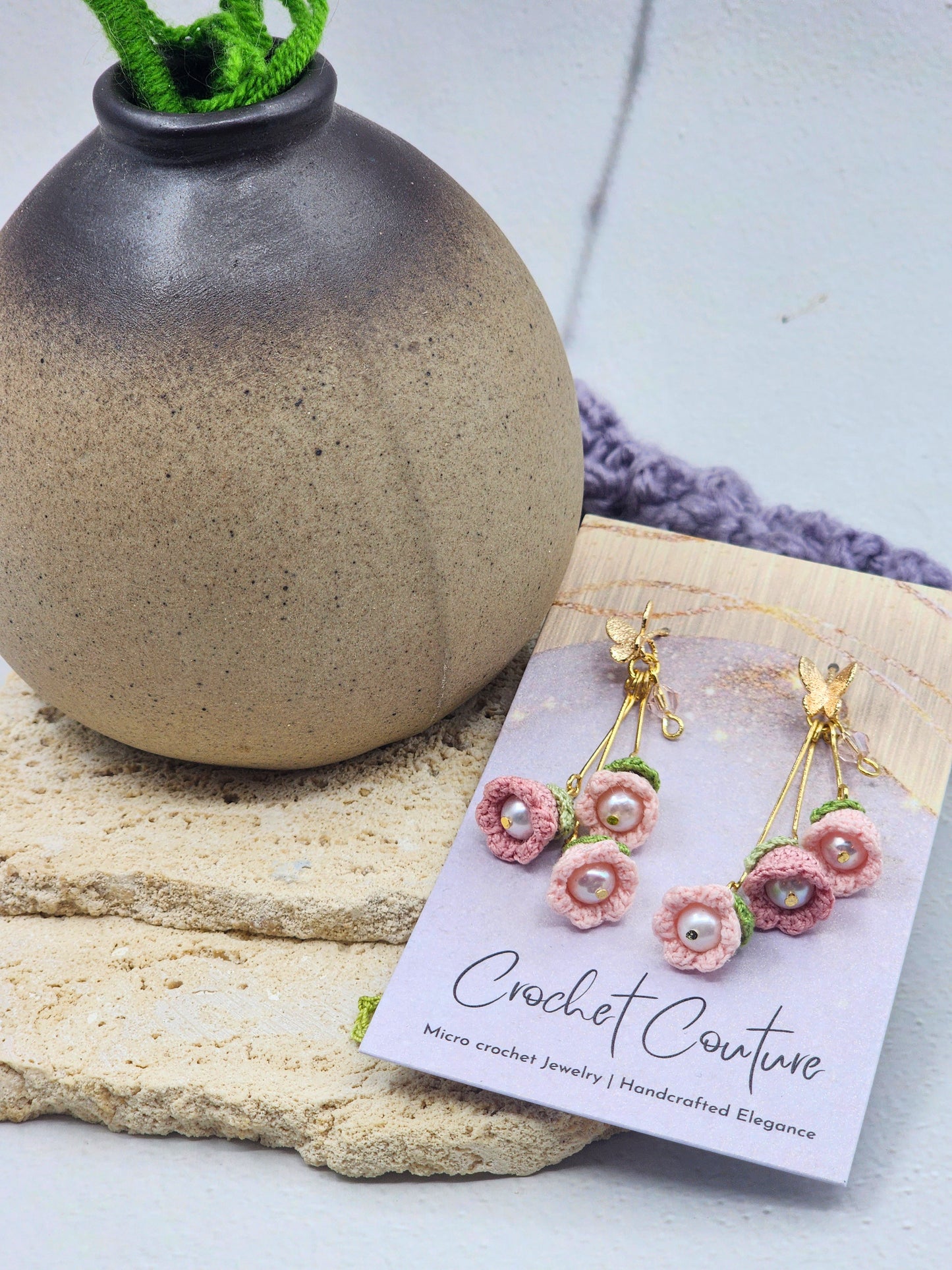 A trio of handcrafted pink micro crochet Lily of the Valley blooms cascade gracefully, each delicately crowned with luminous 6mm Aurora pearls and a sparkling Czech crystal. Finished with 18K gold-plated hooks and findings.