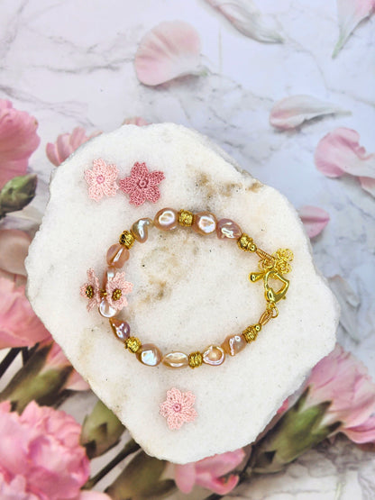 Elevate your style with rare pink-purple radiant Keshi pearls & micro crochet Sakura. 18K gold-plated jewelry wire, spacer beads, & a heart-shaped clasp.