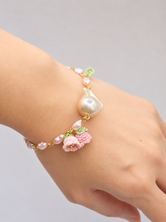 Handcrafted micro crochet Lily of the Valley blooms bracelet. Delicate 4-5mm pink-purple freshwater Baroque pearls decorate an 18K gold-plated chain. At its heart sits an exceptional > 10mm Baroque pearl. 