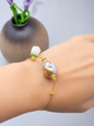 Exceptional metallic baroque pearl bracelet with handcrafted white micro crochet Lily of the Valley bloom. Sparkling cubic zirconia accents on an 18K gold-plated chain. 