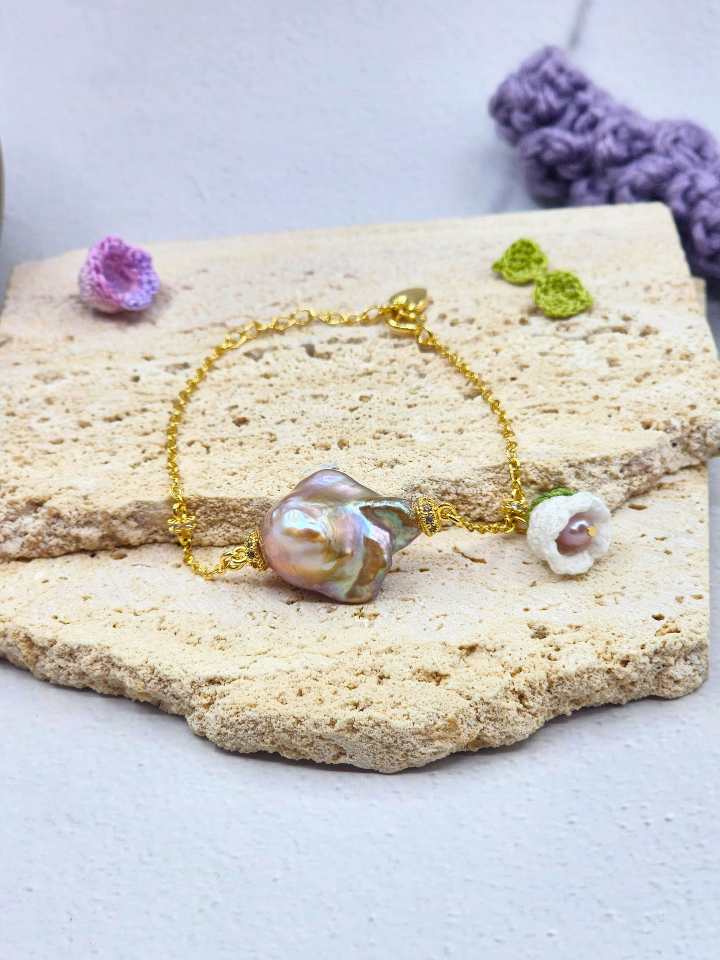 Exceptional metallic baroque pearl bracelet with handcrafted white micro crochet Lily of the Valley bloom. Sparkling cubic zirconia accents on an 18K gold-plated chain. 
